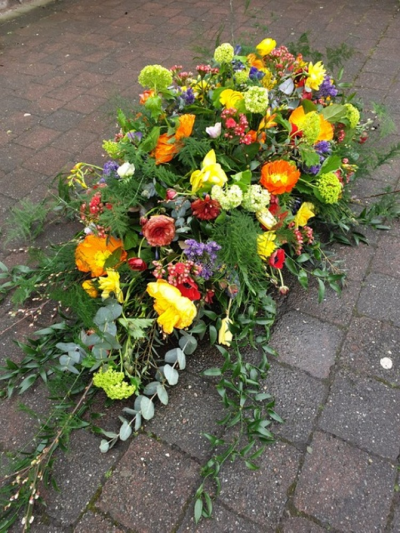 Bright Unstructured Spray - An unstructured spray in bright seasonal flowers for the top of a casket.  Flowers and foliage will change with the seasons.  The spray will cover the top of the casket and trailing naturally.